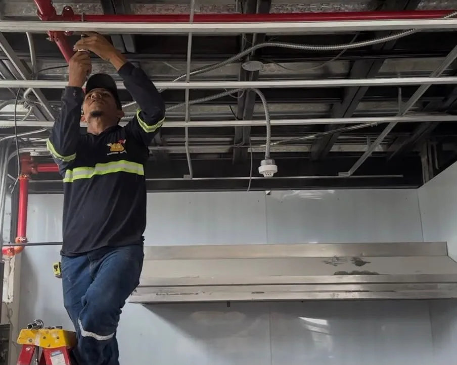 Técnico instalando tubería CI roja — sistema rociadores en edificio